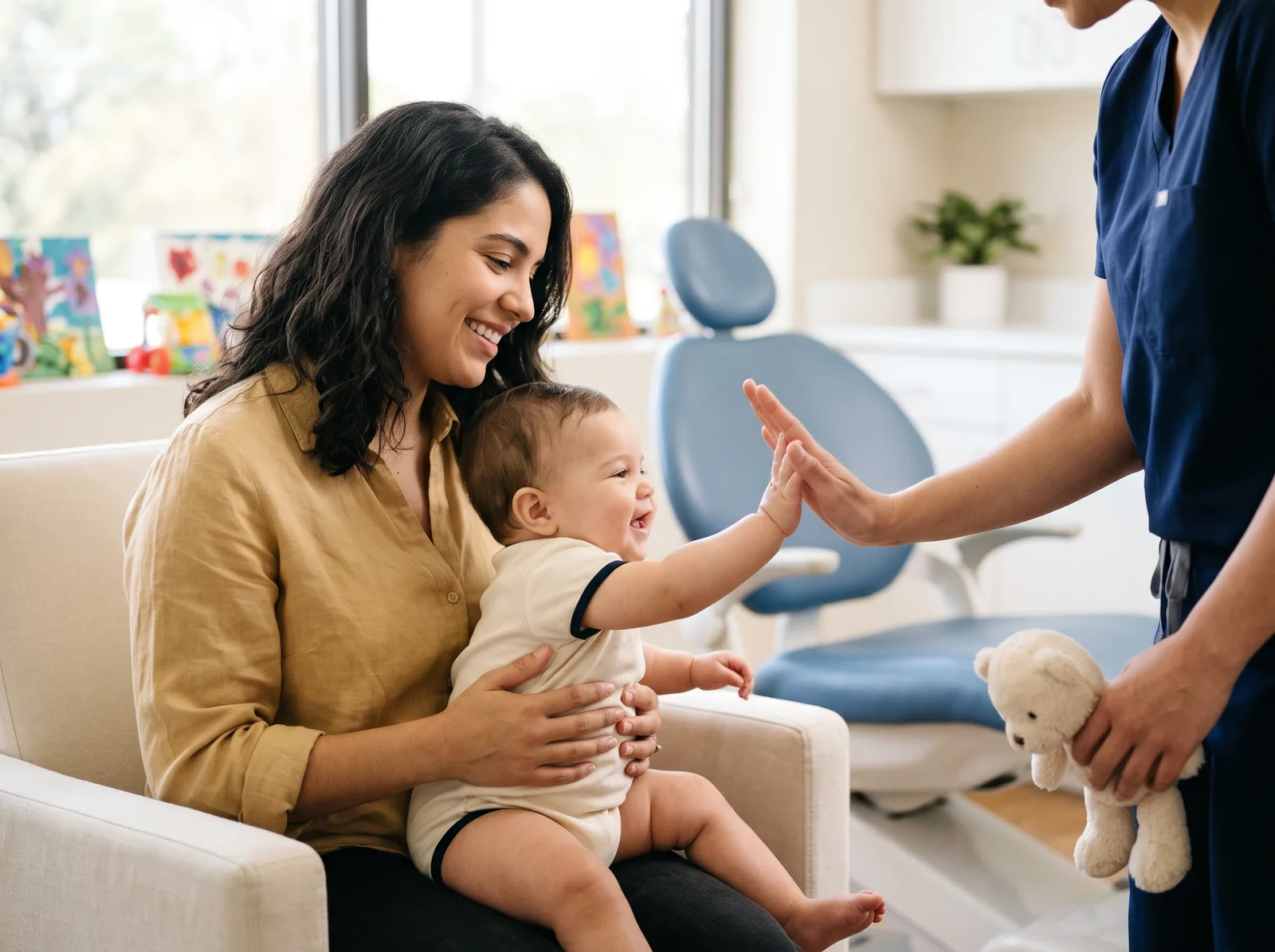 A parent holding a baby who high-fives a dental team member